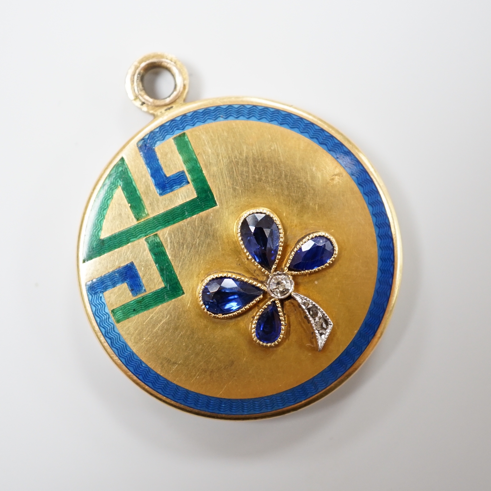 An Art Deco yellow metal, three colour enamel, synthetic? sapphire and diamond set circular locket, with clover motif, diameter 29mm